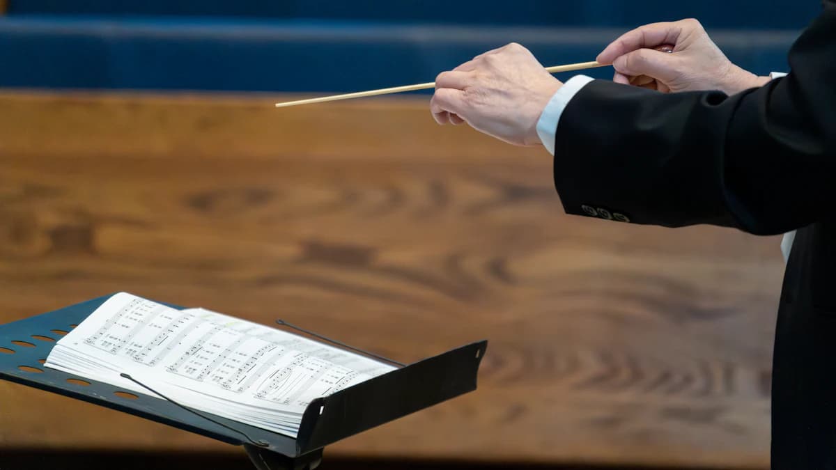 Conductor’s hand holding a baton over a score