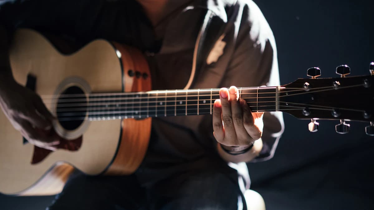 Hands fretting a chord on an acoustic guitar