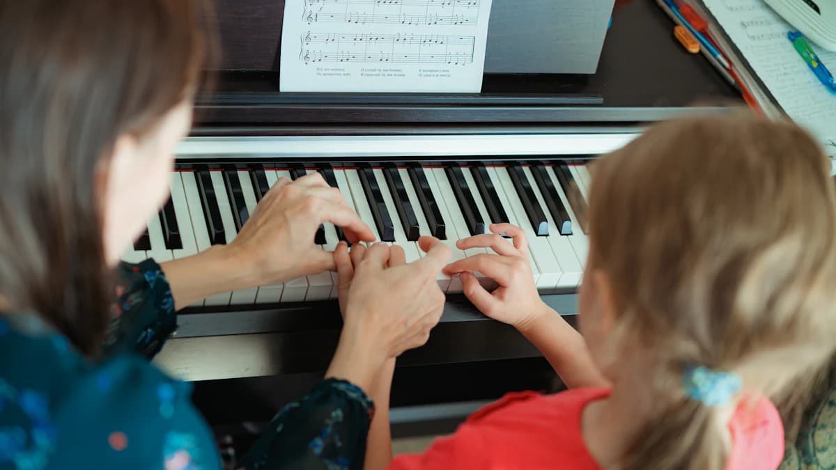 Child learning piano with a teacher
